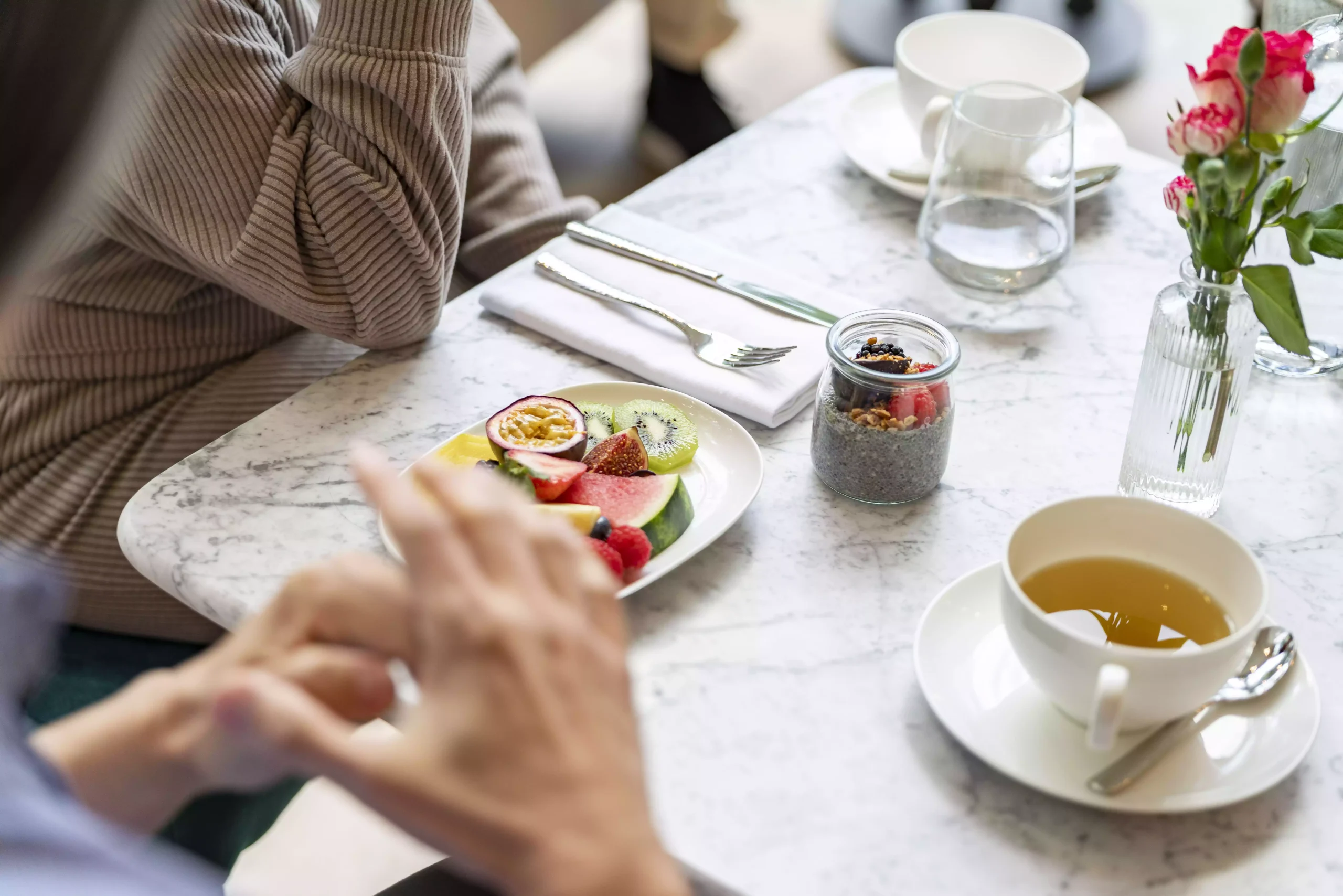 Picture of a dining table with some food items on it and people seating around.