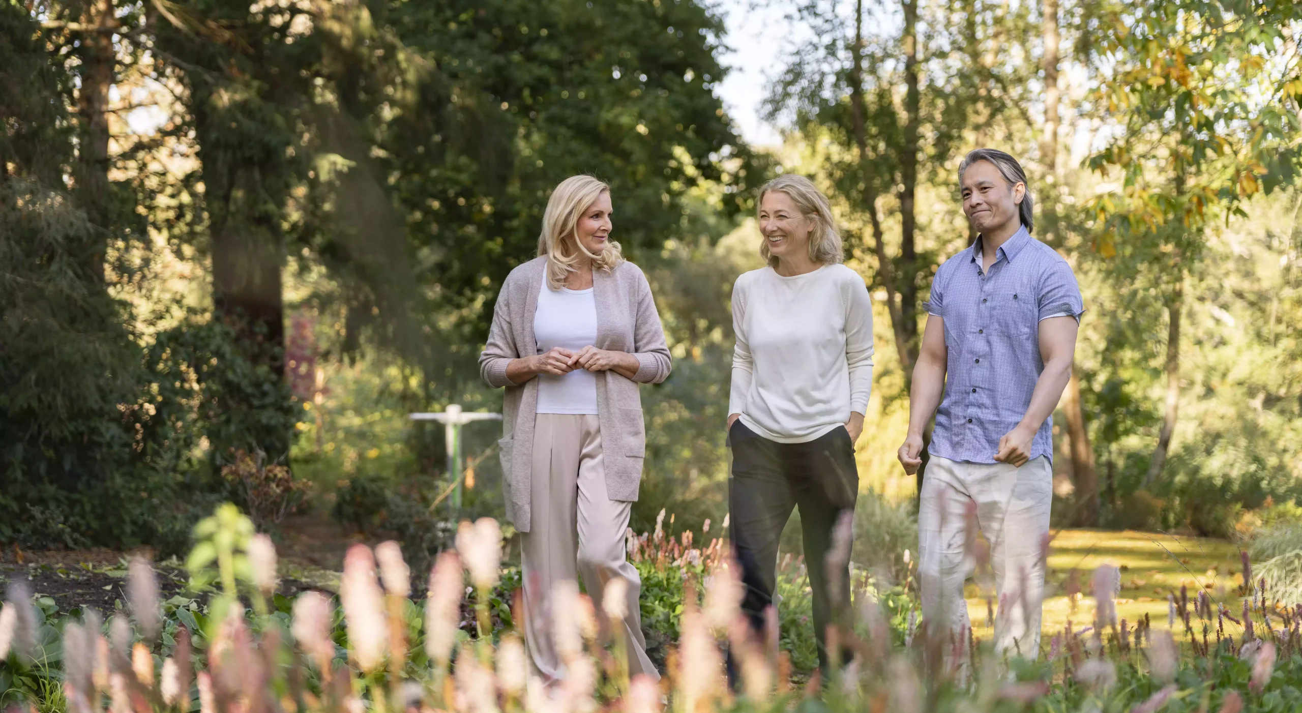 Two women and a man walking in a park.